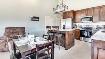 Una cocina moderna con armarios de madera, una isla central y un comedor con sofá de cuero marrón y sillas de madera.