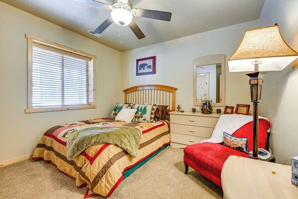 A bedroom with a bed, a dresser, a chair, a ceiling fan, a window with blinds, and a lamp. - < 1 Mi to Brian Head Resort: Spacious Cabin! (Brian Head)