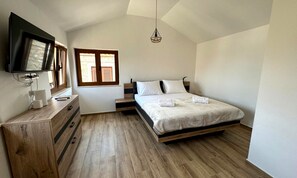A bedroom with a bed, a dresser, a television, and a window.