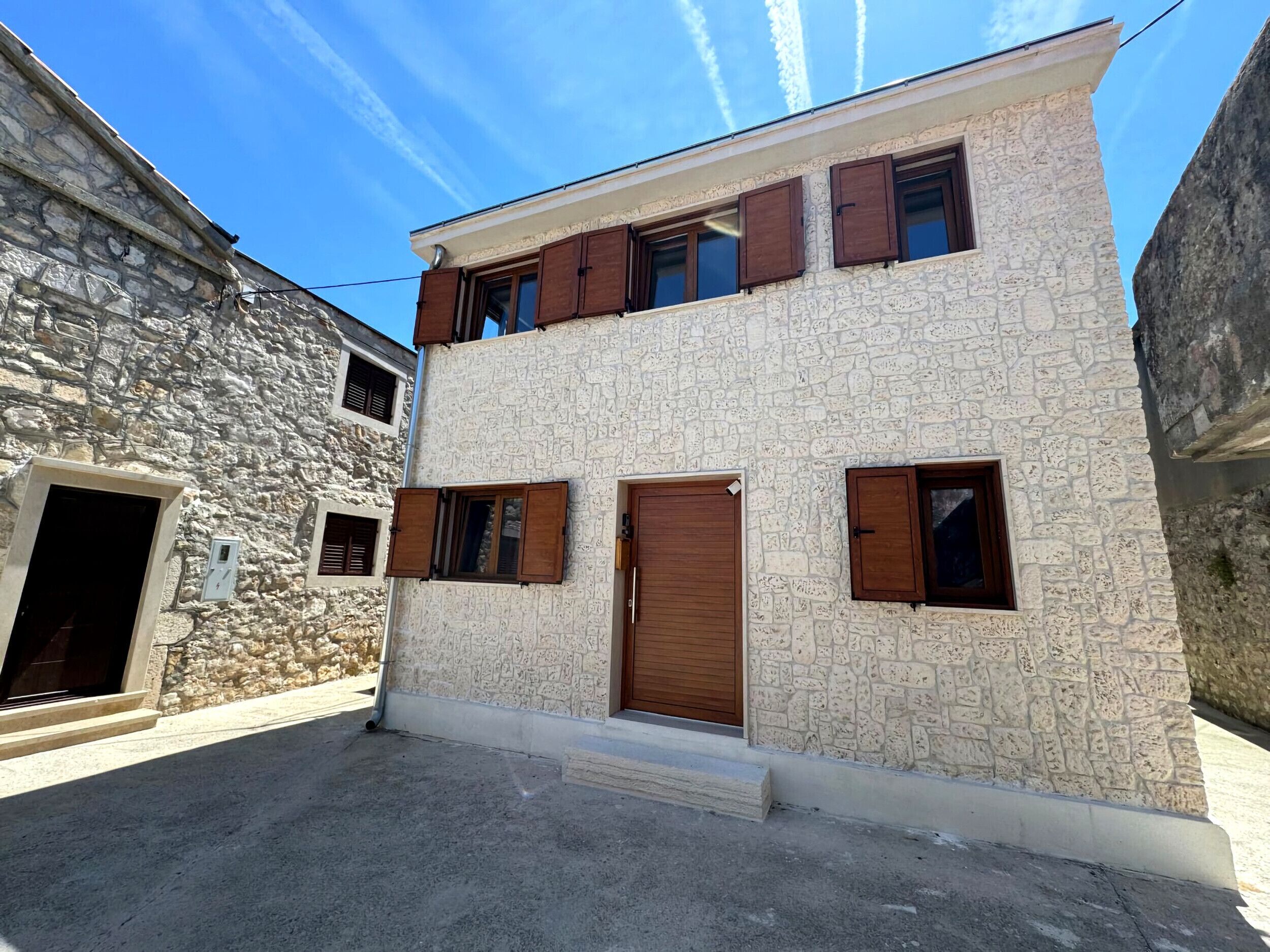 A two-story building with a stone facade and wooden shutters.