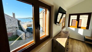 Una habitación con un gran ventanal que da a un puerto deportivo y edificios de piedra.