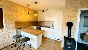 Cocina compacta con una isla de madera, taburetes de bar, horno empotrado y estufa negra.