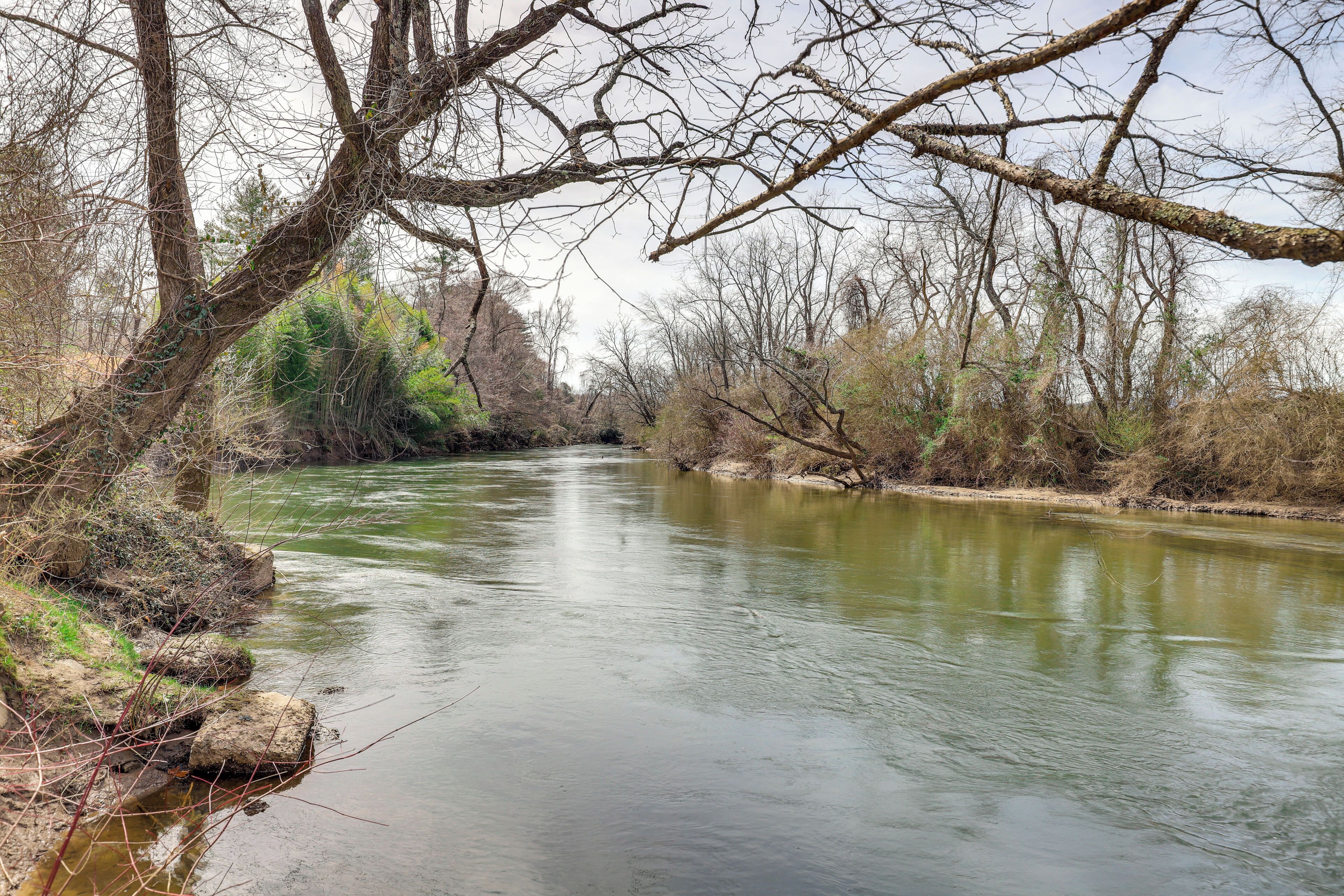 A river with a rocky bank and leafless trees.