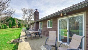 A deck with outdoor furniture, a covered patio, and a house with a chimney.