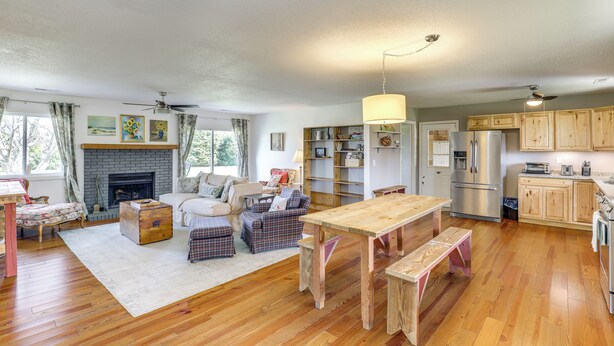 A spacious living room with a fireplace, wooden flooring, and a dining area with benches.