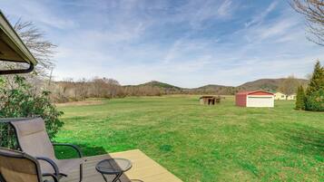Relax on the deck with a table and chairs, surrounded by rolling hills and lush trees.