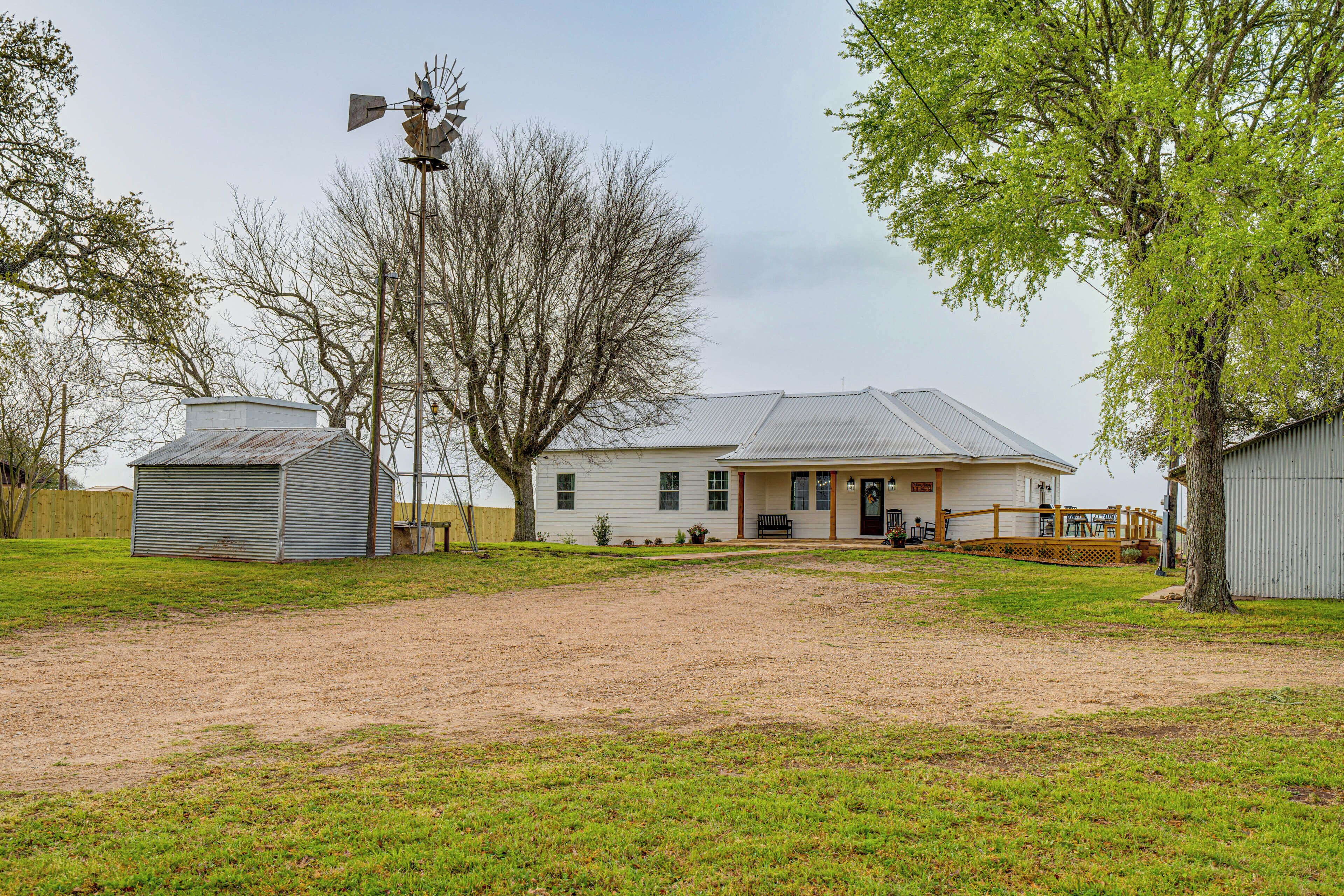 A single-story house with a metal roof, a front porch, and a fenced yard.