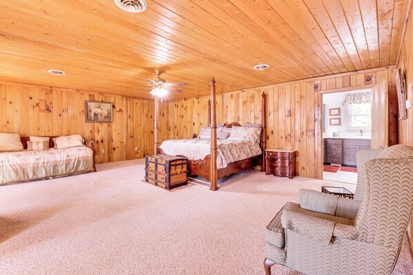 A wooden-paneled room with a bed, a chair, and a chest of drawers.
