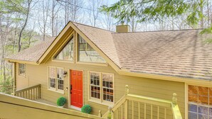 A two-story house with a red door, multiple windows, and a wooden deck. - Serenity Now: Big Canoe Mountain Home! (Jasper)