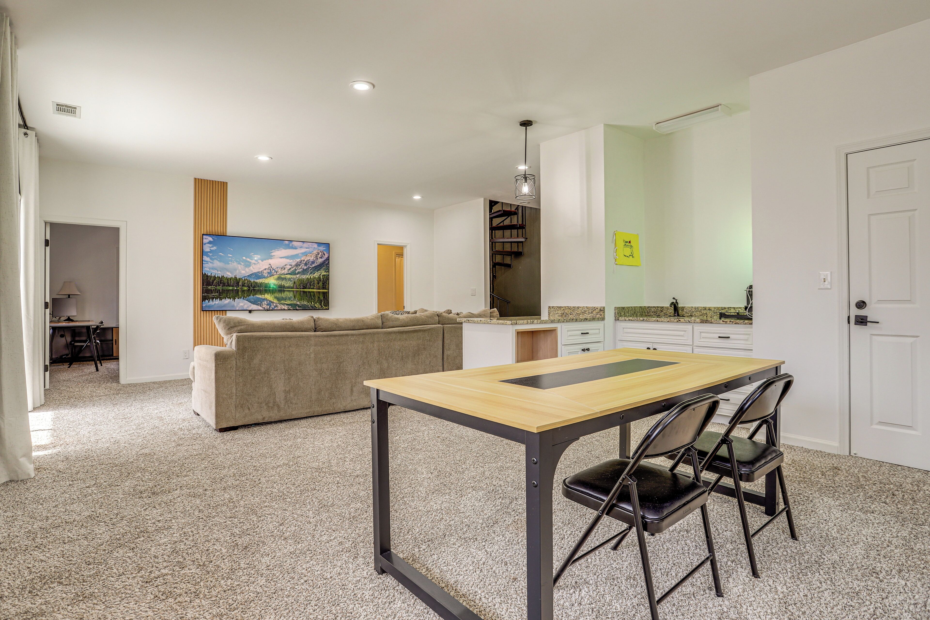 Een moderne keuken met een houten tafel en stoelen, een bank en een schilderij aan de muur.