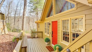 A wooden deck with a bench, a red door, and a welcome mat. - Serenity Now: Big Canoe Mountain Home! (Jasper)