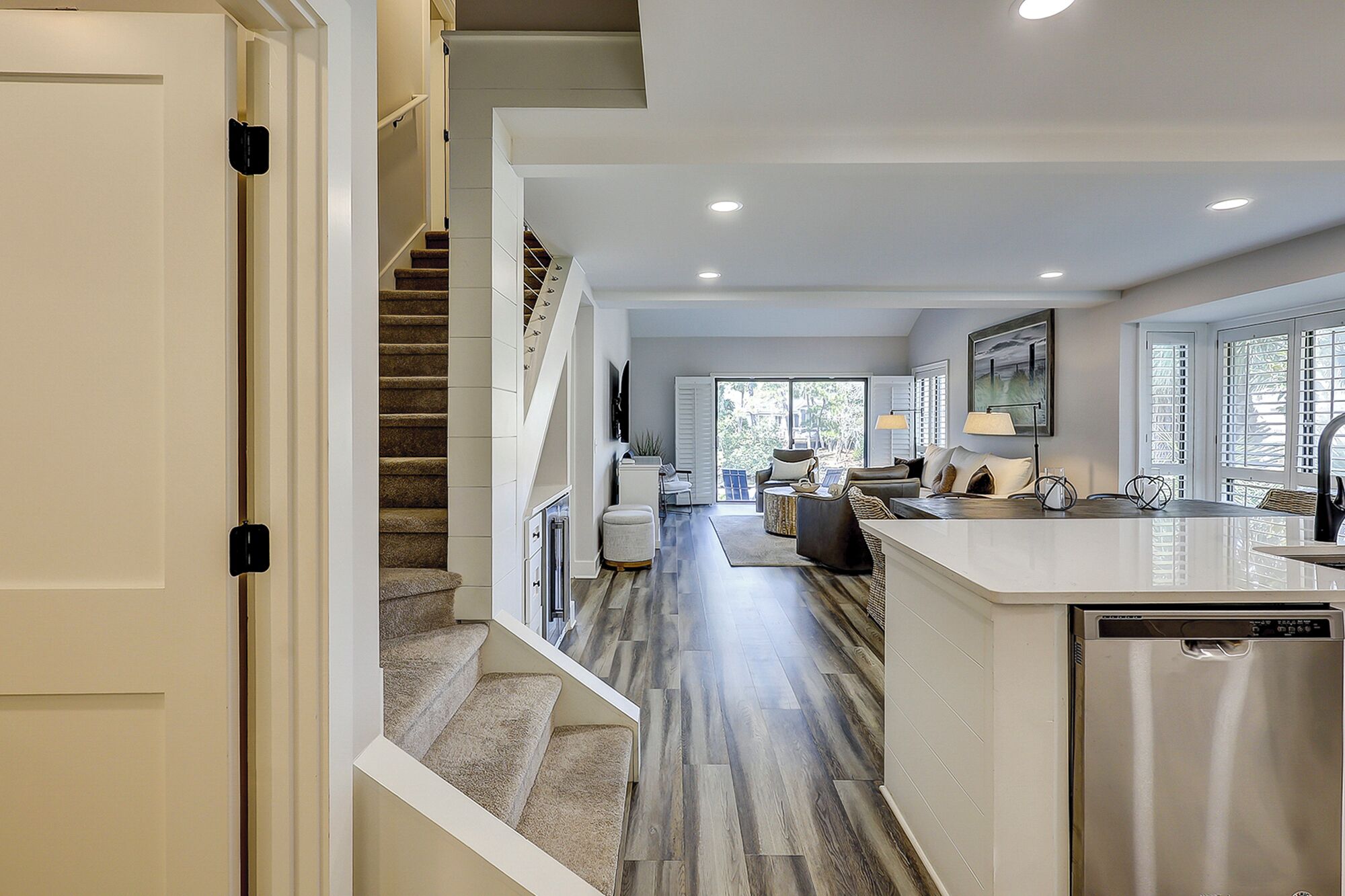 A spacious kitchen with a central island, a dining area with a table and chairs, and a staircase leading to an upper level.