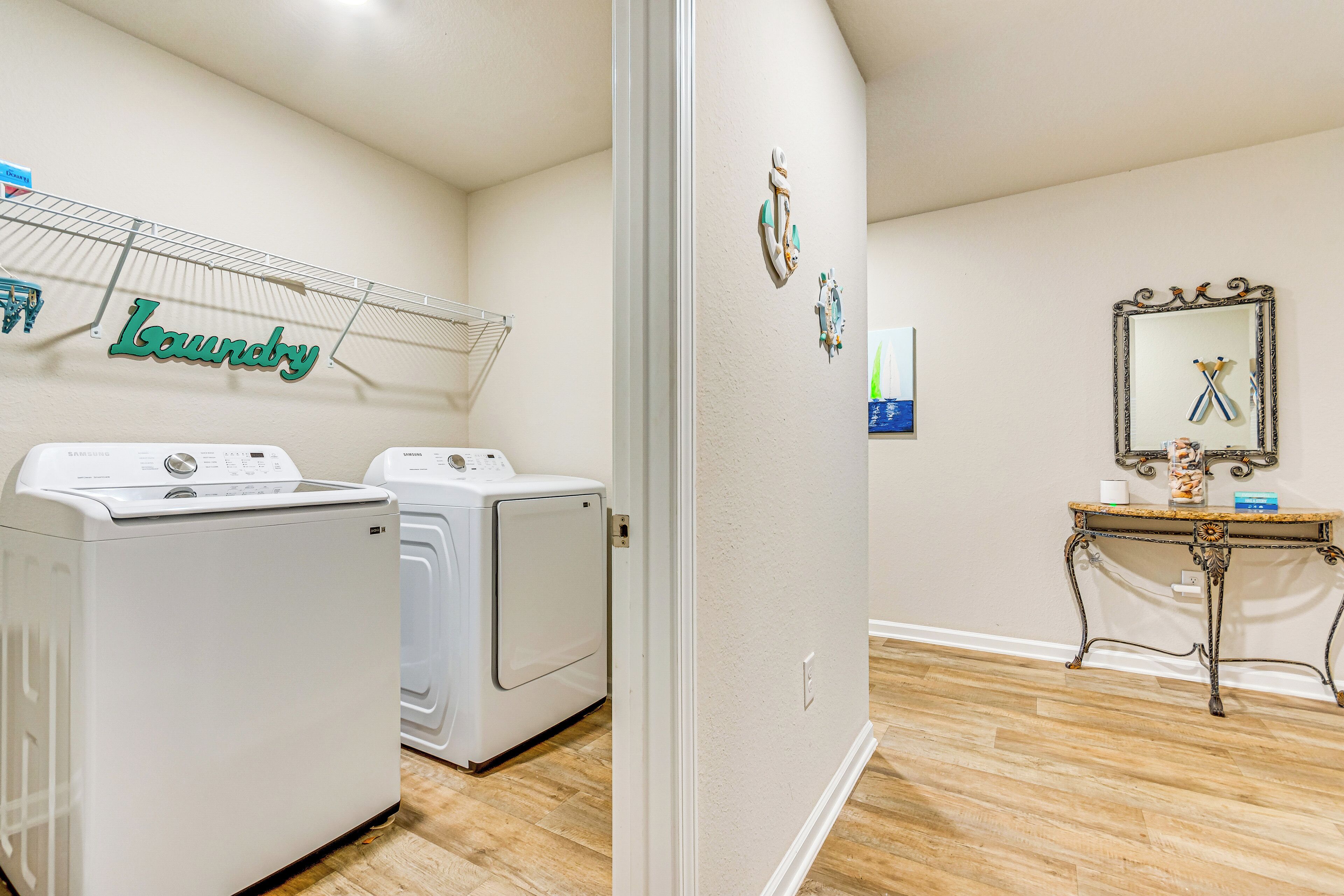 A laundry room with two washing machines, a drying rack, and a mirror on the wall.