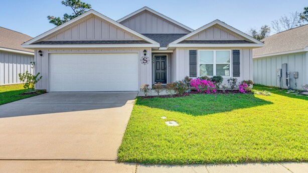 A single-story house with a garage, a well-maintained lawn, and a small garden with pink flowers. - 6 Mi to Gulf Shores Beach: Family Getaway! (Foley)