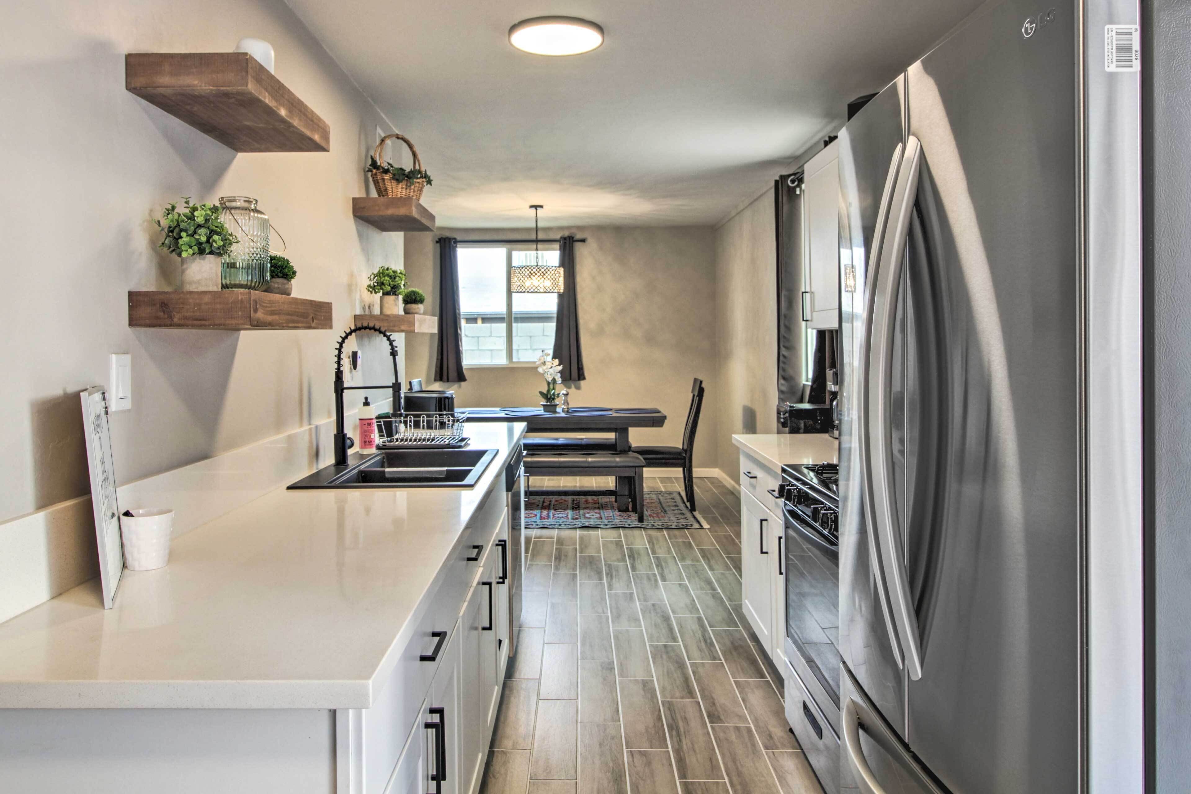 A modern kitchen with a stainless steel refrigerator, wooden shelves, and a dining area with a table and chairs.