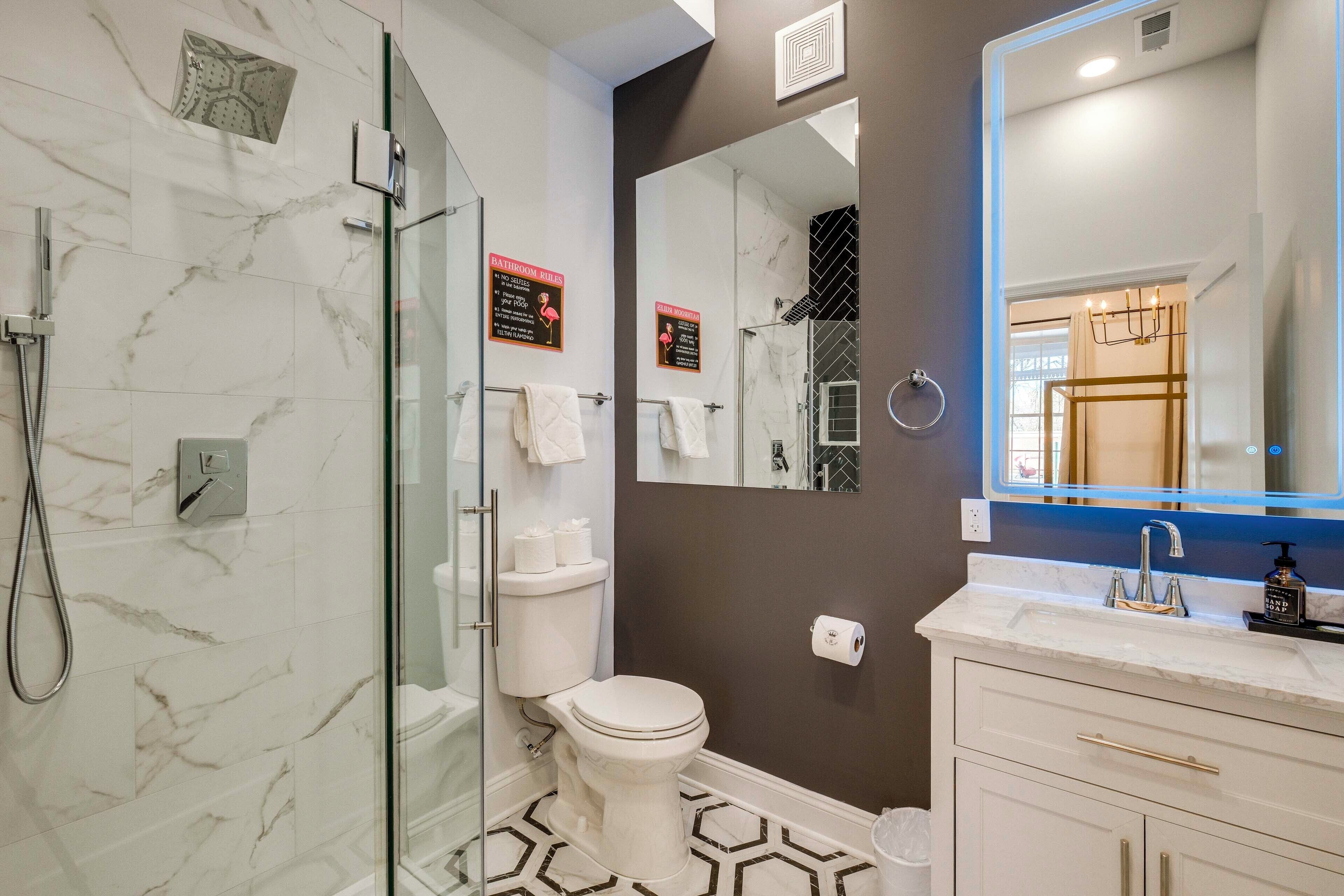 A modern bathroom with a glass-enclosed shower, a toilet, a sink with a mirror, and a towel rack.
