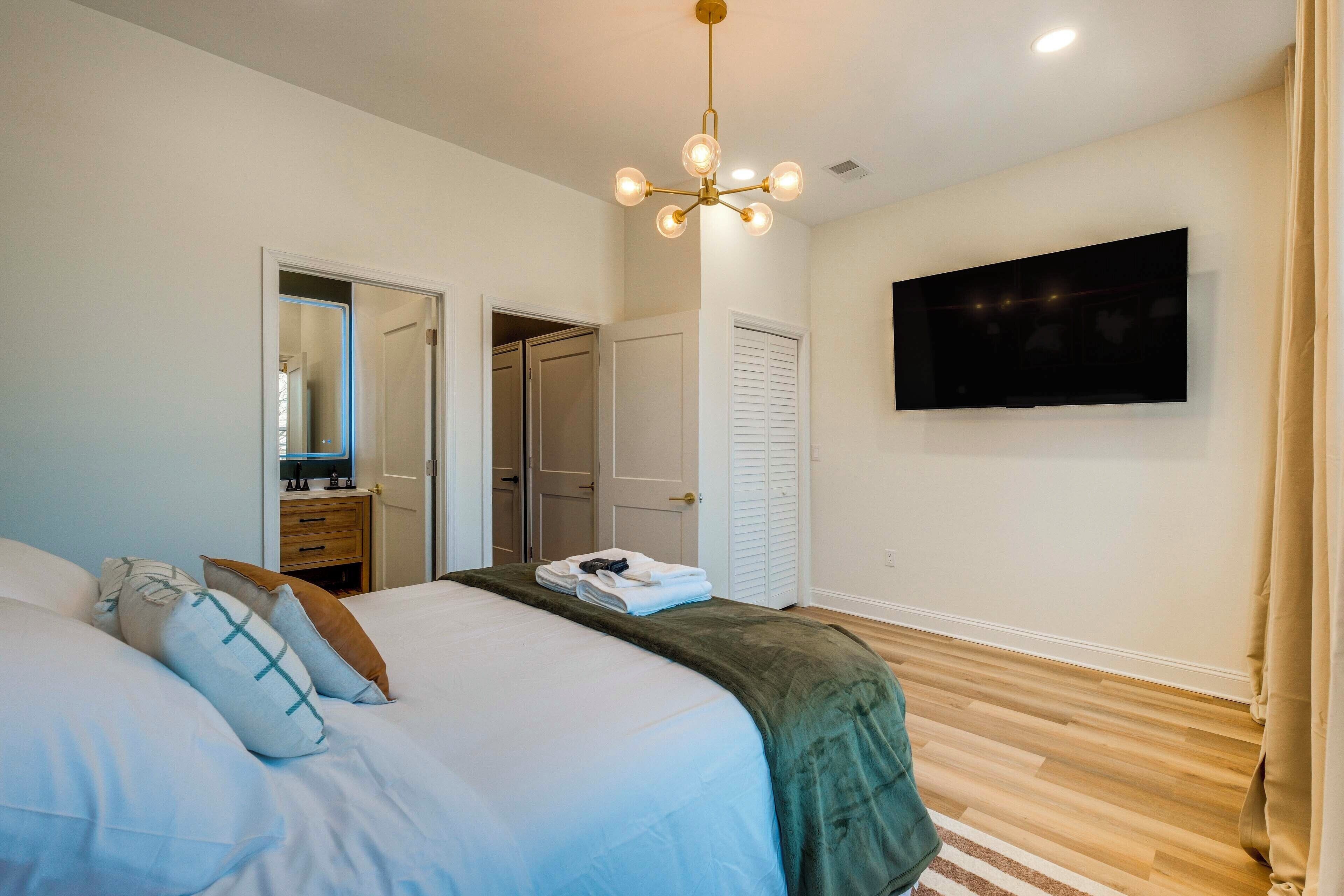 A bedroom with a bed, a television mounted on the wall, and a door leading to a closet.