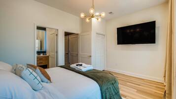 A bedroom with a bed, a television mounted on the wall, and a door leading to a closet.