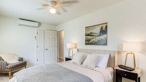 A bedroom with a bed, a chair, a nightstand with lamps, a ceiling fan, and a painting on the wall. - 4 Mi to Dtwn: Dog-friendly Fayetteville Home (Fayetteville)