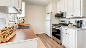A modern kitchen with white cabinets, stainless steel appliances, and a wooden countertop. - 4 Mi to Dtwn: Dog-friendly Fayetteville Home (Fayetteville)