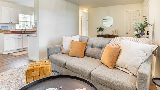A living room with a grey sofa, a round coffee table, and a woven ottoman. - 4 Mi to Dtwn: Dog-friendly Fayetteville Home (Fayetteville)
