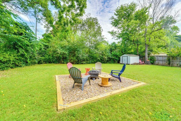 A backyard with a wooden deck, outdoor furniture, and a small shed.