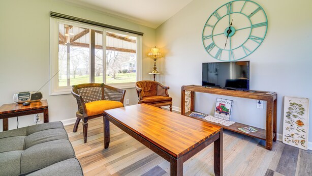 A living room with a wooden coffee table, a sofa, a television, and a large wall clock. - 3 Mi to Caesars Casino: Indiana Retreat w/ Patio! (New Albany)