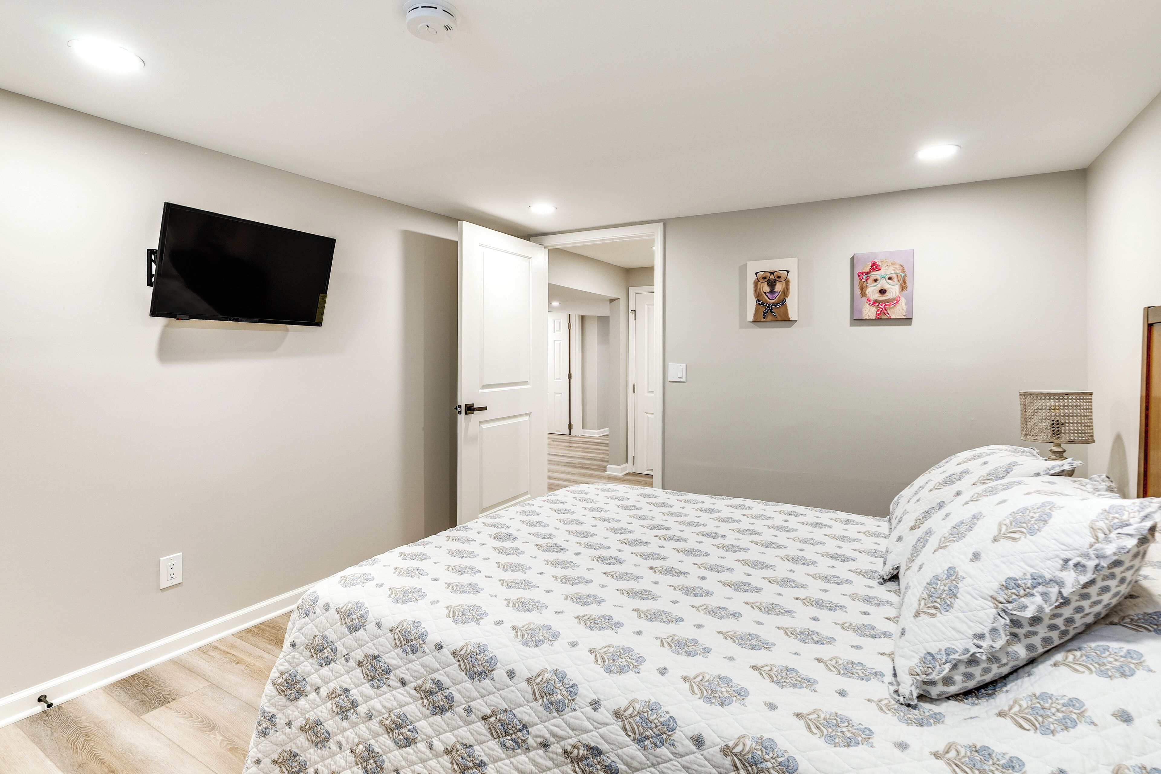 Une chambre à coucher avec un lit, un téléviseur fixé au mur et deux tableaux accrochés au mur.