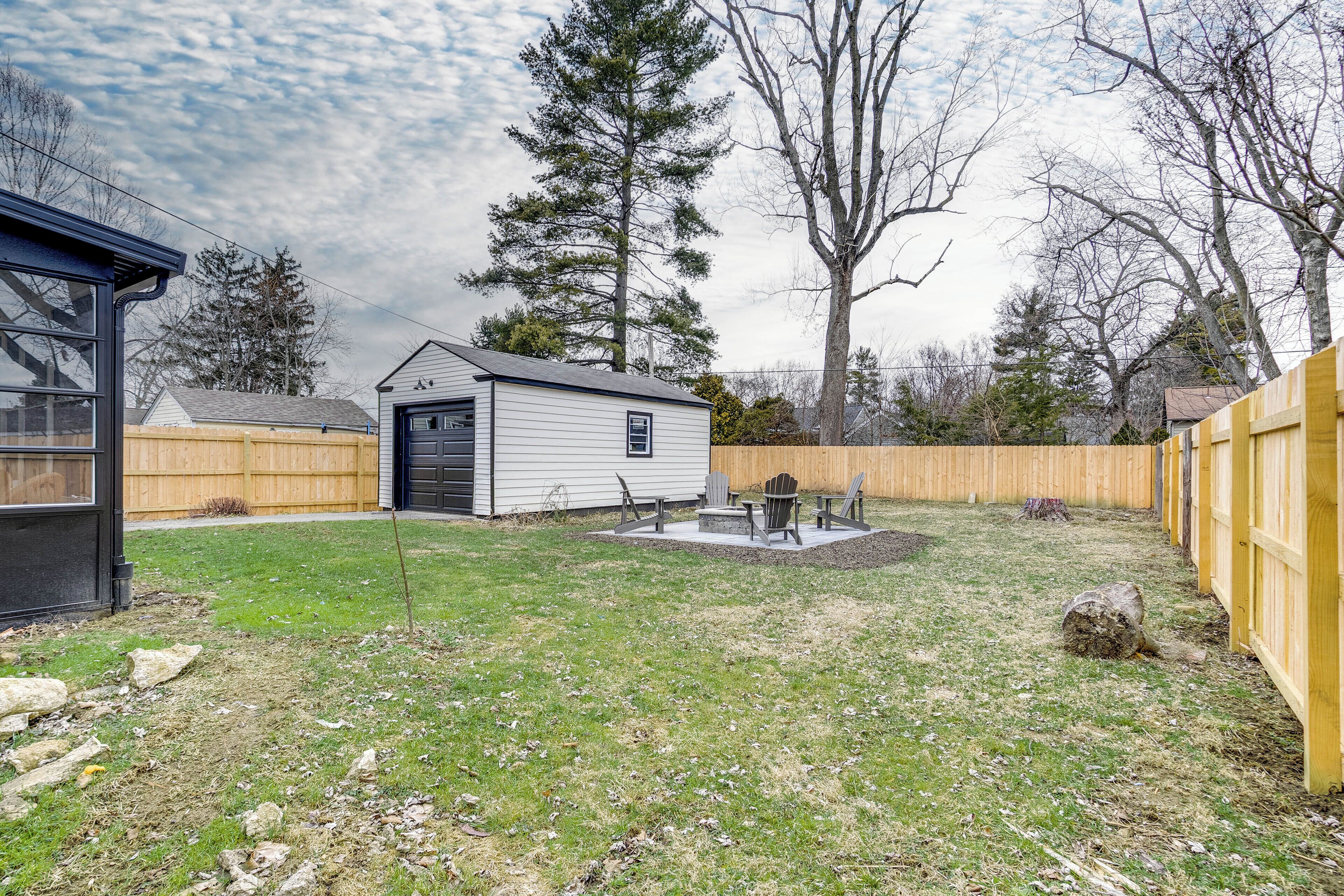 A backyard with a wooden deck, a shed, and a fire pit area.