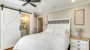 A bedroom with a large bed, a nightstand, a ceiling fan, and a sliding door. - Screened Patio & Fire Pit: Modern Westerville Home (Westerville)