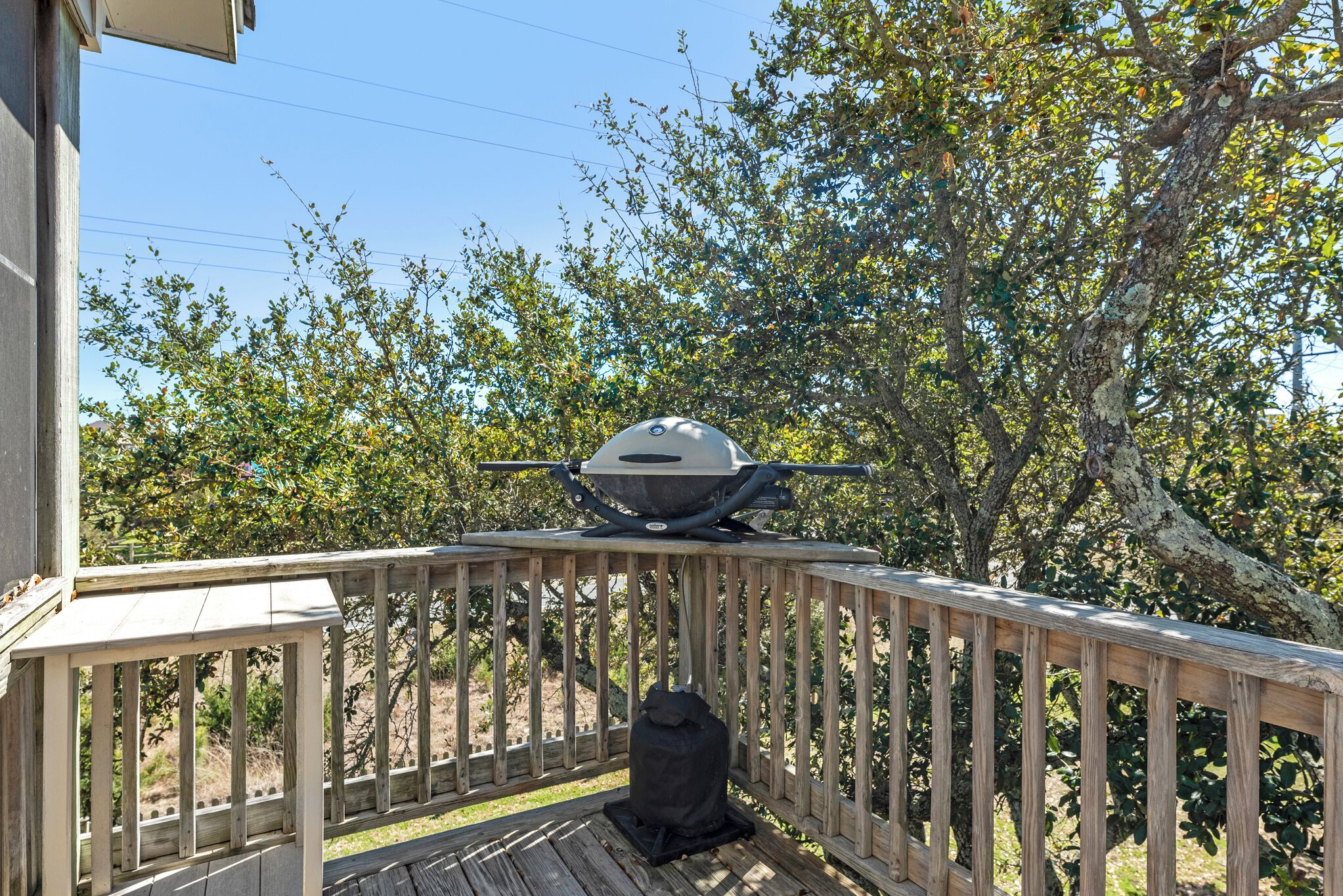 Una terraza de madera con una parrilla barbacoa en el porche de una casa.