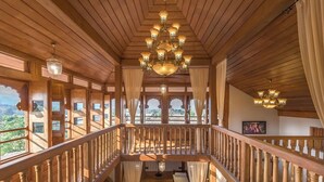 A wooden interior with a staircase, chandeliers, and large windows. - CosmicStays Parambi Farm- Vintage Charm  (Bhor)