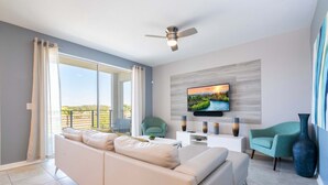 A modern living room with a sofa, two chairs, a TV, and a ceiling fan.