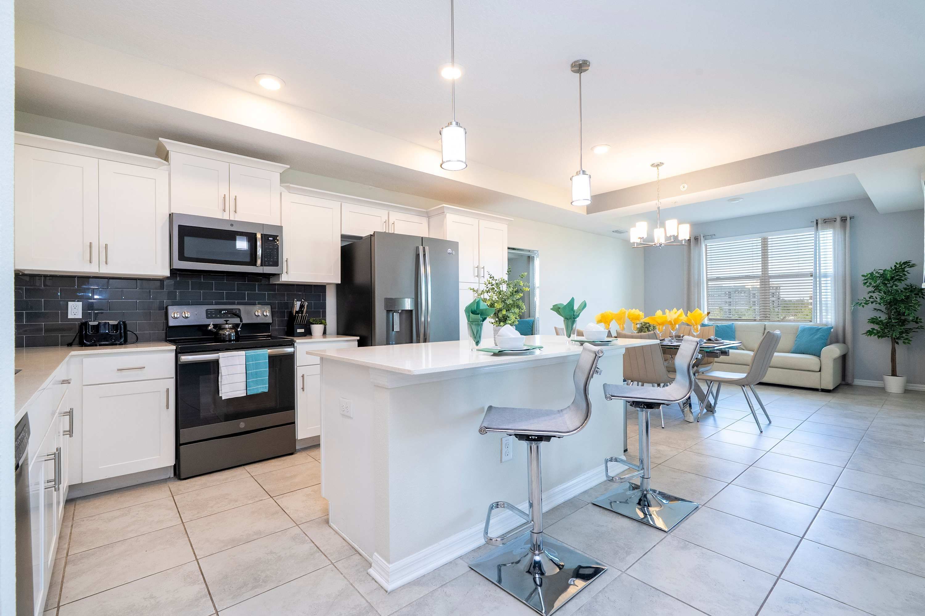 A modern kitchen with white cabinets, stainless steel appliances, and a central island with bar stools.