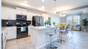 A modern kitchen with white cabinets, stainless steel appliances, and a central island with bar stools.