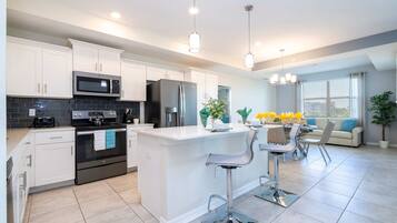 A modern kitchen with white cabinets, stainless steel appliances, and a central island with bar stools.