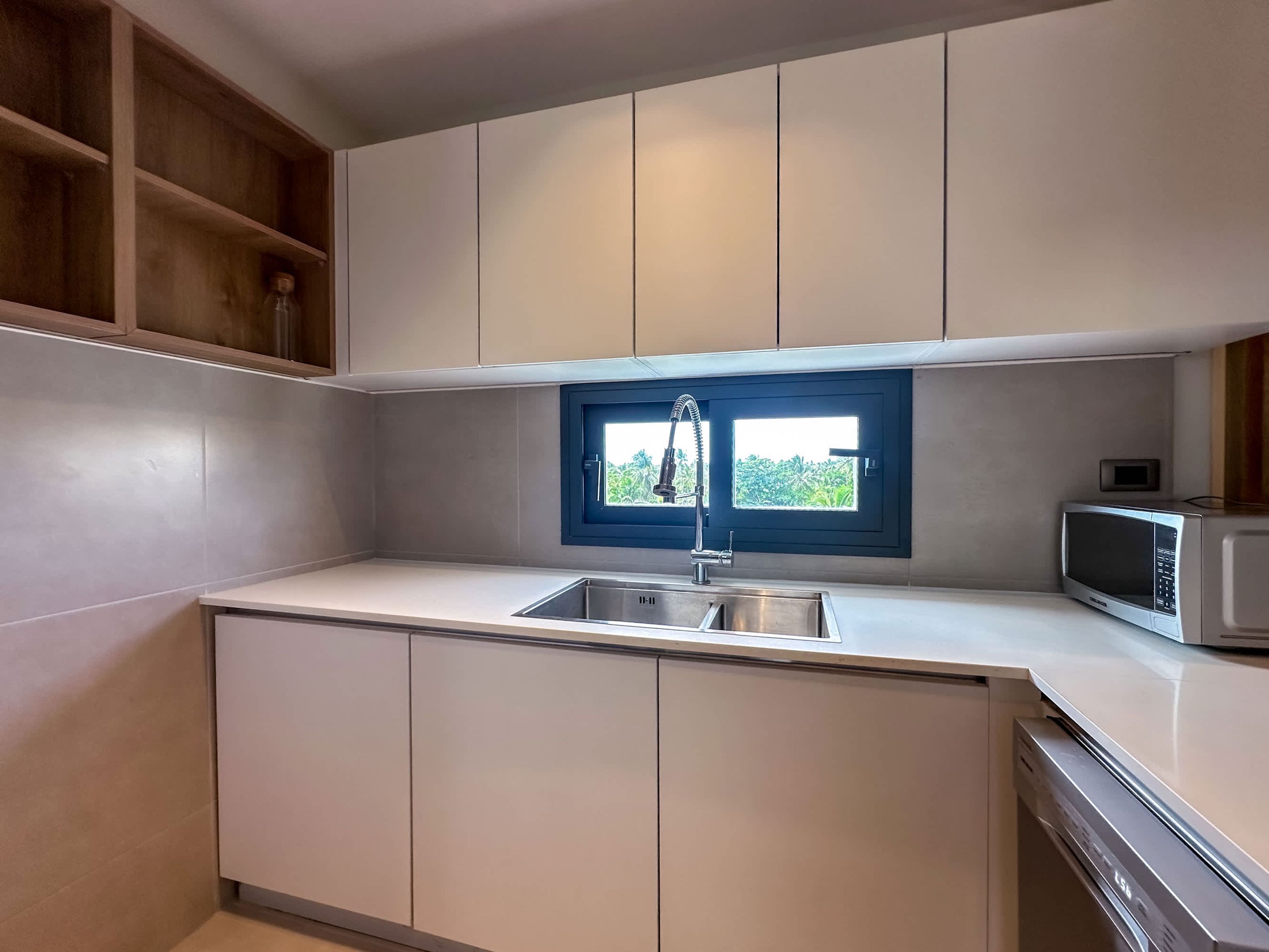 Cozinha moderna com pia embutida, janela com vista e micro-ondas.