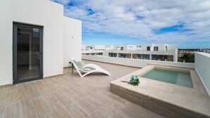 A rooftop terrace with a pool, a lounge chair, and a glass door leading to an indoor area. - 4 Bedroom Beach Penthouse w Private Rooftop (Punta Cana)