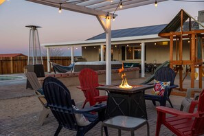An outdoor patio with Adirondack chairs, a fire pit, and a hammock. - Desert Oasis Cozy Comfort Meets Outdoor Luxury (Twentynine Palms)