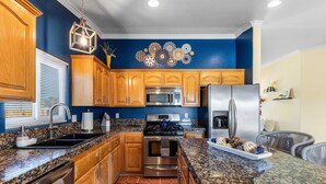 A kitchen with wooden cabinets, a stainless steel refrigerator, a microwave, and a stove. - Desert Oasis Cozy Comfort Meets Outdoor Luxury (Twentynine Palms)