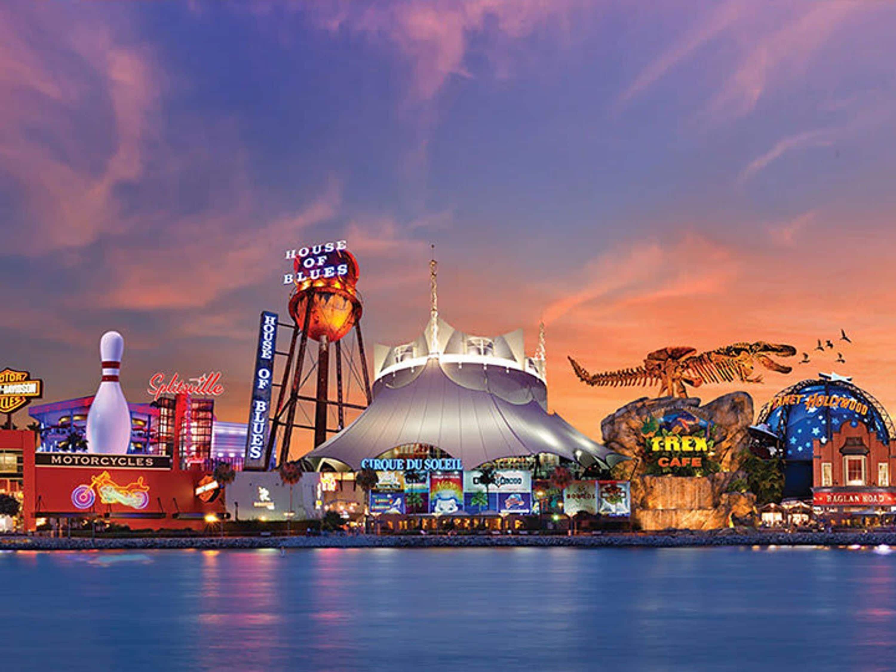 A waterfront entertainment complex with a large dome structure, a bowling alley, and various illuminated signs.