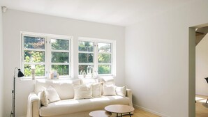 A room with a white sofa, two small round tables, and a floor lamp. - 5 Star Holiday Home in Liseleje (Liseleje)