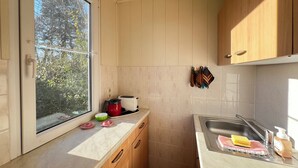 A kitchen with wooden cabinets, a window, a toaster, a kettle, and a sink with a soap dispenser. - Cozy bungalow vacation idyll (Koserow)