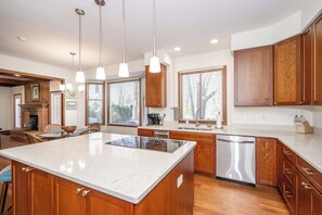 A modern kitchen with wooden cabinets, a large island, and pendant lighting. - Luxurious Dream Home  - For 10! (Loveland)