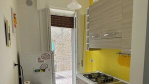 Une cuisine équipée d’une cuisinière à gaz, d’un réfrigérateur et d’un mur jaune.