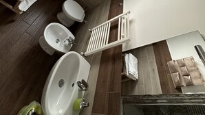 Une salle de bain moderne équipée d’un lavabo, de toilettes, d’un bidet et d’une petite fenêtre.