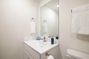 A bathroom with a white sink, a mirror, a toilet, and two towels hanging on towel racks. - 205 Close to downtown, Landing and Convention Center (Branson)