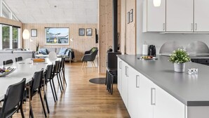 A modern kitchen with white cabinets, a central island, and a large window. - 5 Star Holiday Home in Albaek (Aalbaek)