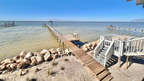 A wooden pier extending into calm waters, with a gazebo at the end and a staircase leading to a covered area. - Bayside Cottage bayfront home with private dock (St. George Island)