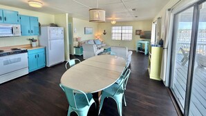 A compact kitchen with a dining area, a TV, and a view through a sliding glass door. - Bayside Cottage bayfront home with private dock (St. George Island)